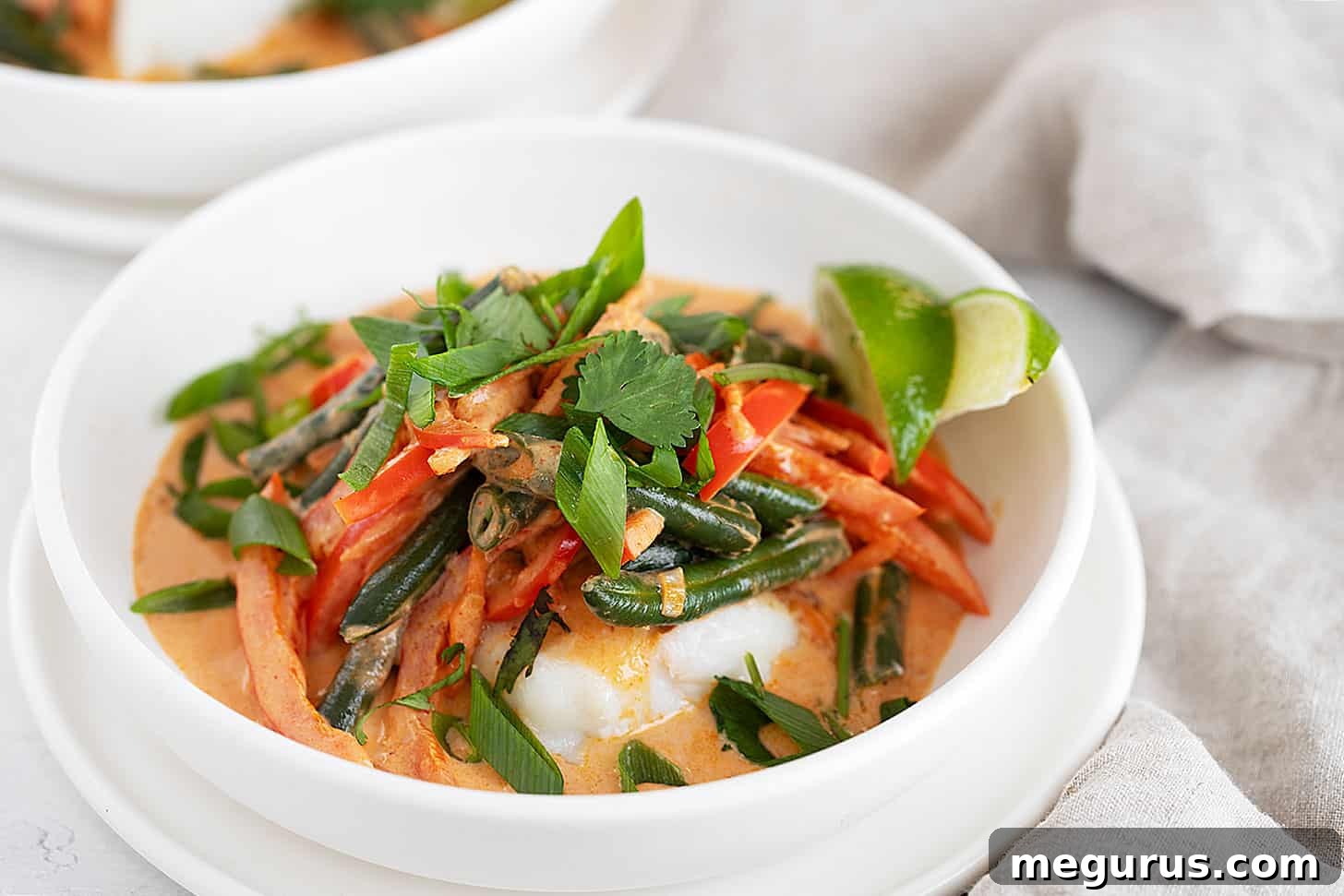 A bowl of vibrant Thai red curry fish with fresh herbs