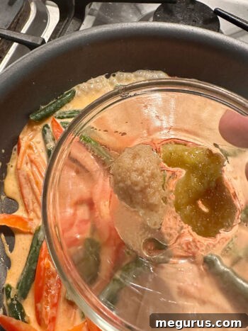 Adding ginger paste and lemongrass paste to the simmering curry sauce