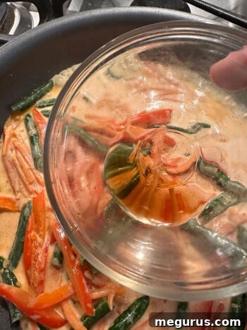 Adding fish sauce to the Thai red curry sauce in the skillet