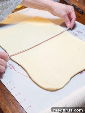 Rolling one half of the dough into a large, thin rectangle.