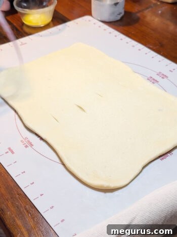 Scoring the rolled dough lightly to mark where the strips will be cut.
