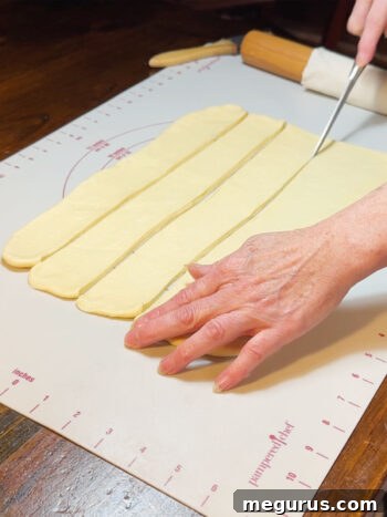 Using a pizza cutter to cut the dough into uniform strips.
