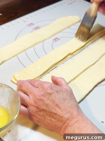 Carefully stacking a second dough strip on top of the first.