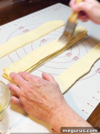 The process of stacking and buttering dough strips, showing multiple layers.