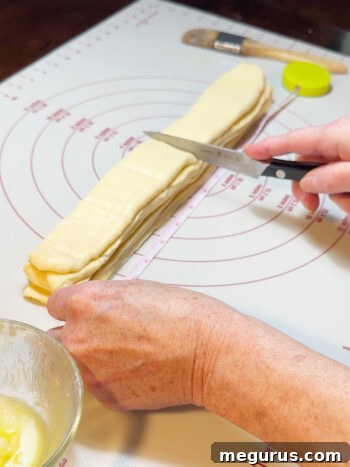 Scoring the stacked dough strips to mark the individual roll portions.