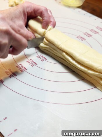Cutting the stacked dough into individual pieces for the rolls.