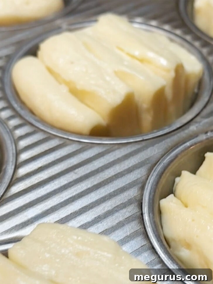 Fully risen butterflake rolls in a muffin tin, expanded and ready for baking.