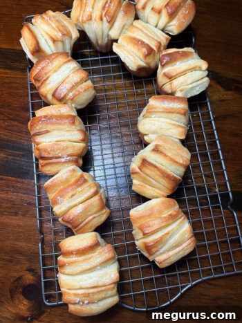 Butterflake rolls cooling on a wire rack, still warm and showing their tender layers.