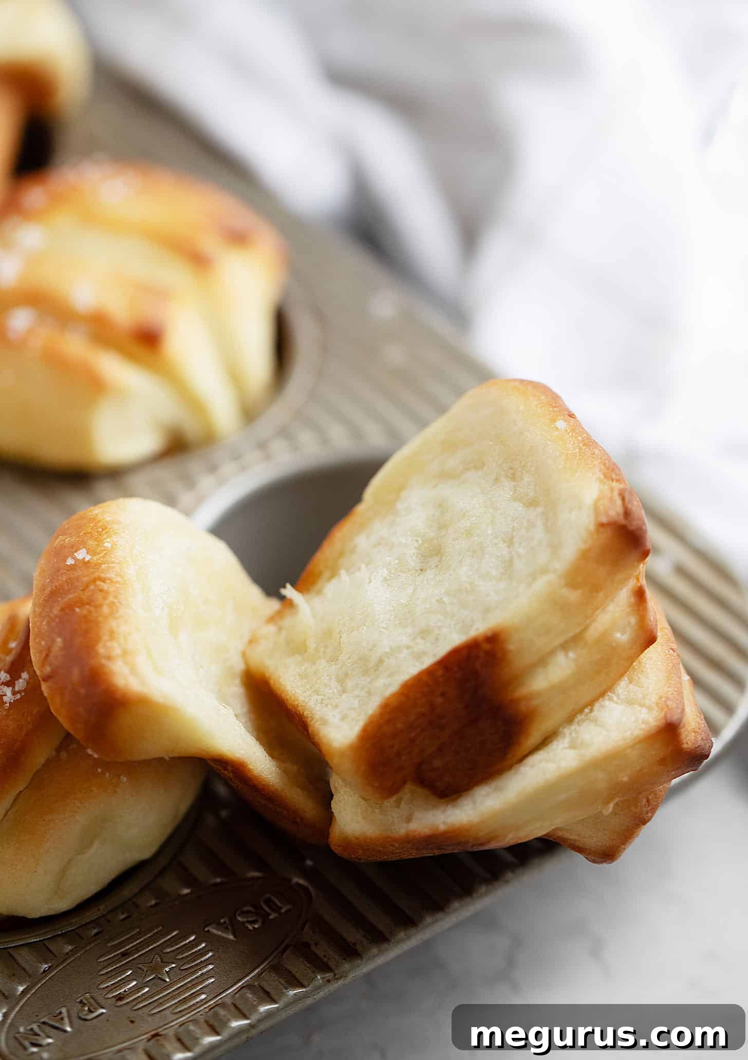 A freshly baked butterflake roll split open, revealing its soft, fluffy, and tender interior layers.