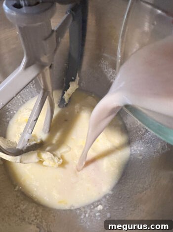 Yeast mixture being poured into the mixing bowl with other wet ingredients.