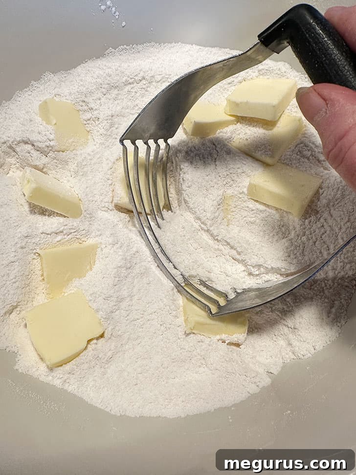 Cold butter cubes being cut into the dry ingredients with a pastry blender