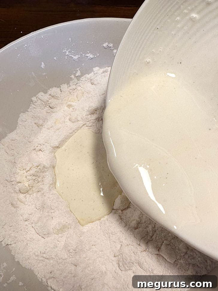 Cream, egg, and vanilla mixture being added to the dry ingredients in a bowl