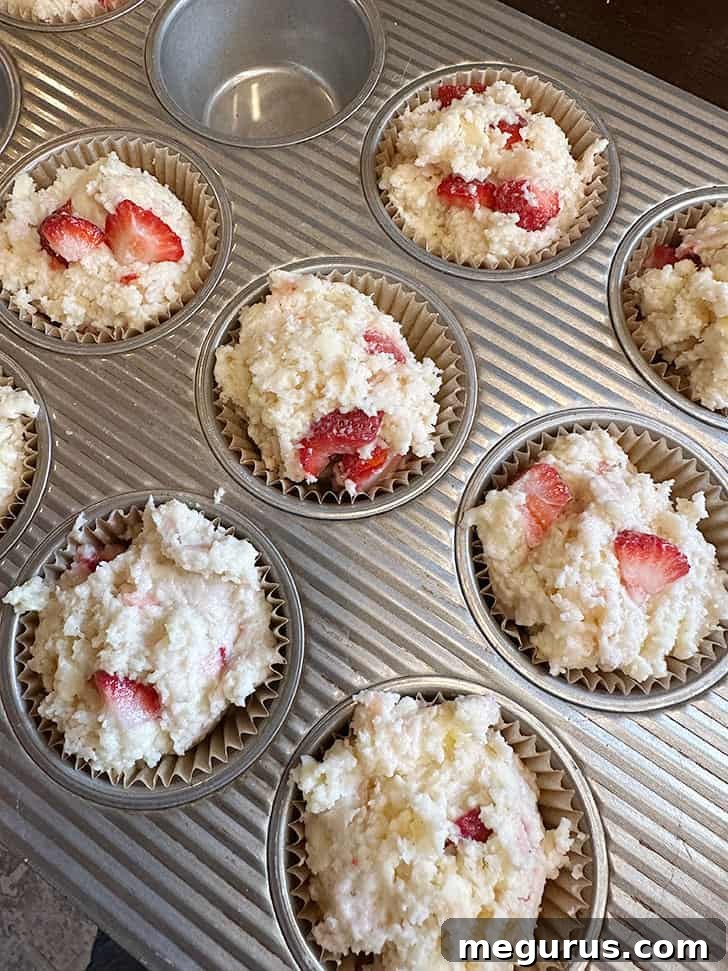 Muffin dough scooped into a muffin tin before baking, showing generous portions
