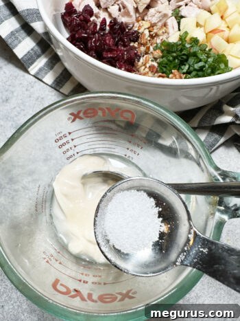 Adding salt to the dressing ingredients in a measuring cup.