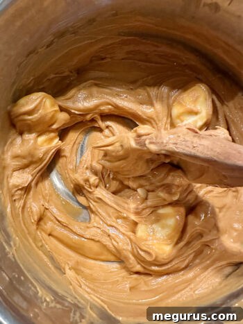 The peanut butter, butterscotch, and butter mixture melting slowly over medium heat, stirred gently.