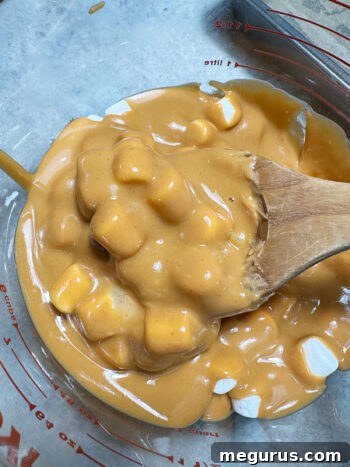 Gently stirring the peanut butter mixture and marshmallows together until all marshmallows are evenly coated.
