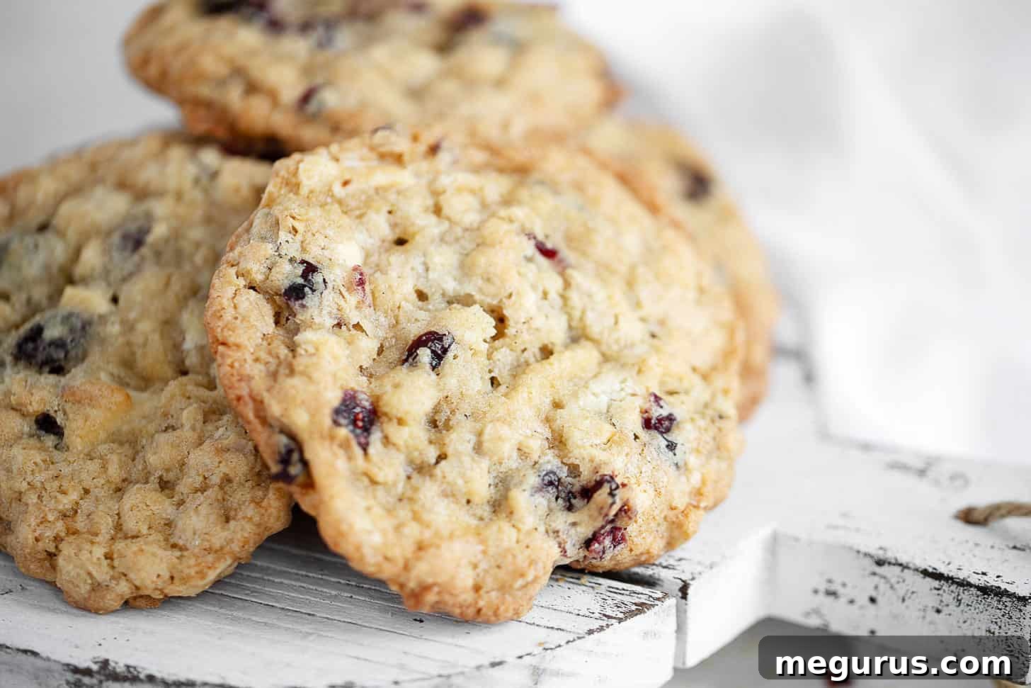 Freshly baked cranberry oatmeal white chocolate cookies arranged beautifully on a rustic serving board, ready to be enjoyed.