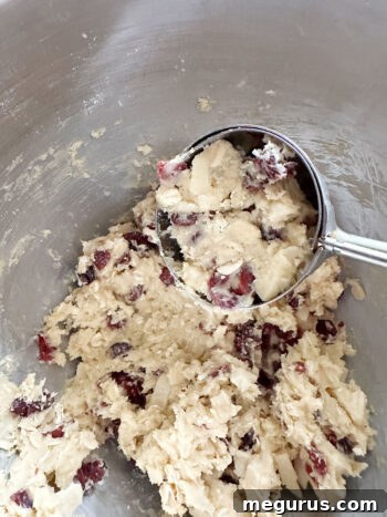 Using a cookie scoop to portion out uniform balls of dough onto a baking sheet.