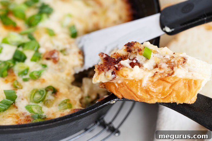 Hot onion dip in cast iron skillet with bread slices for dipping.