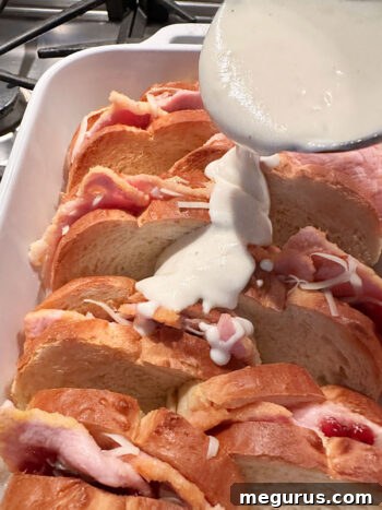 pouring Mornay sauce generously over assembled sandwiches