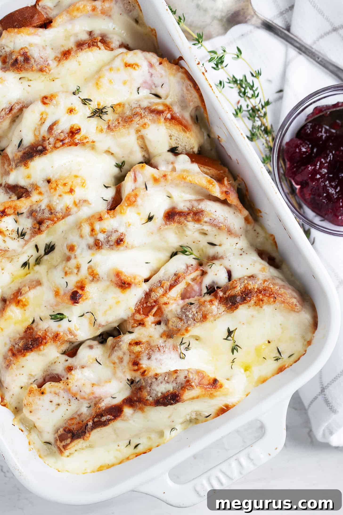 Close-up of baked Croque Monsieur casserole with golden crust and cranberry sauce on the side