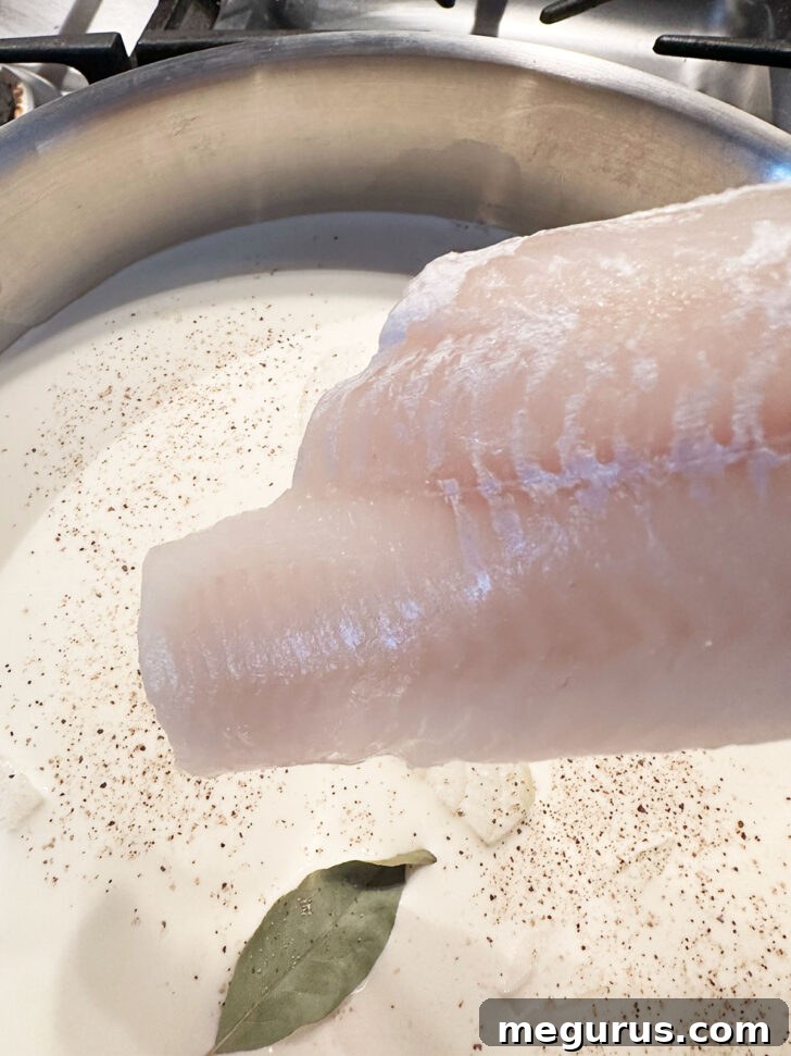 Adding fish fillets to a skillet with milk and cream mixture