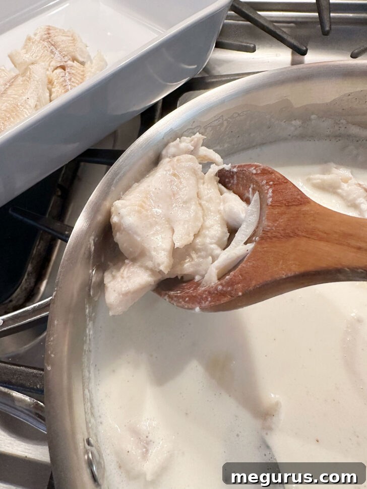 Removing poached fish from the skillet with a slotted spoon