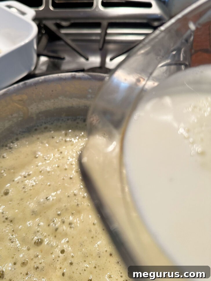 Gradually adding reserved milk mixture to the butter and flour mixture, whisking to combine