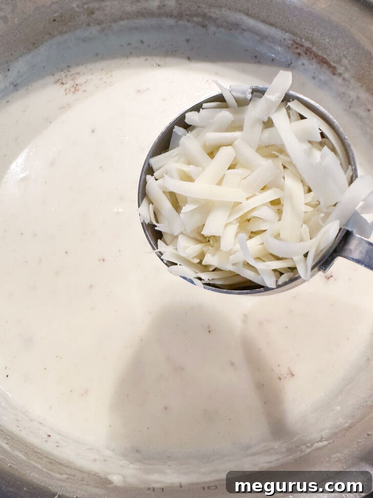 Stirring Gruyere cheese into the thickened white sauce off the heat