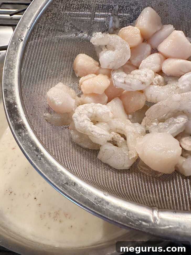 Adding shrimp and scallops to the creamy white sauce