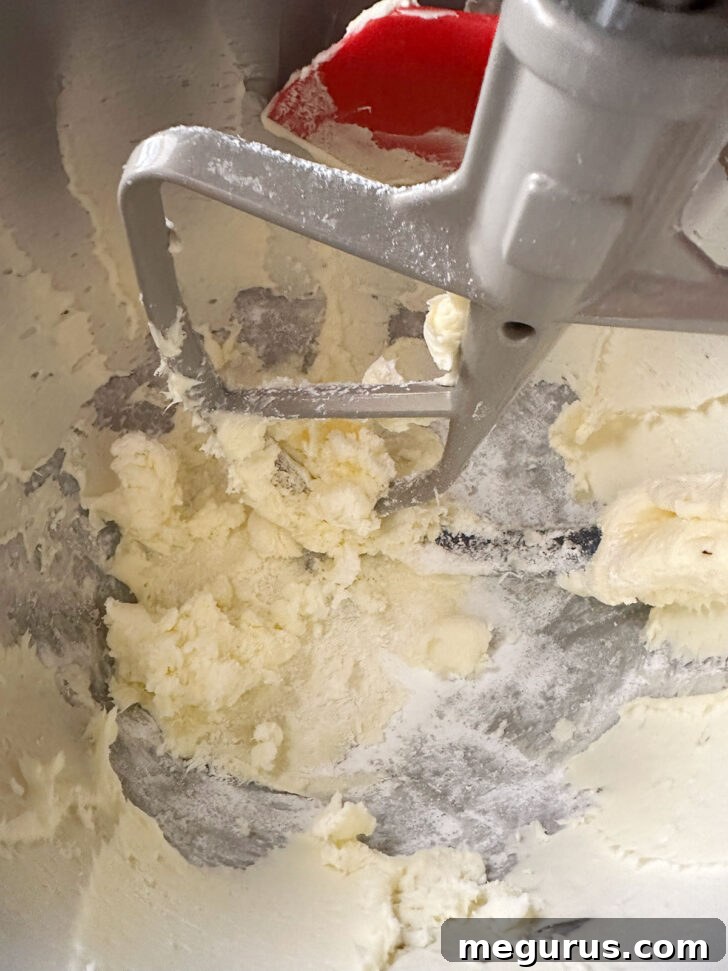 Beating butter and icing sugar in a bowl, scraping down the sides.