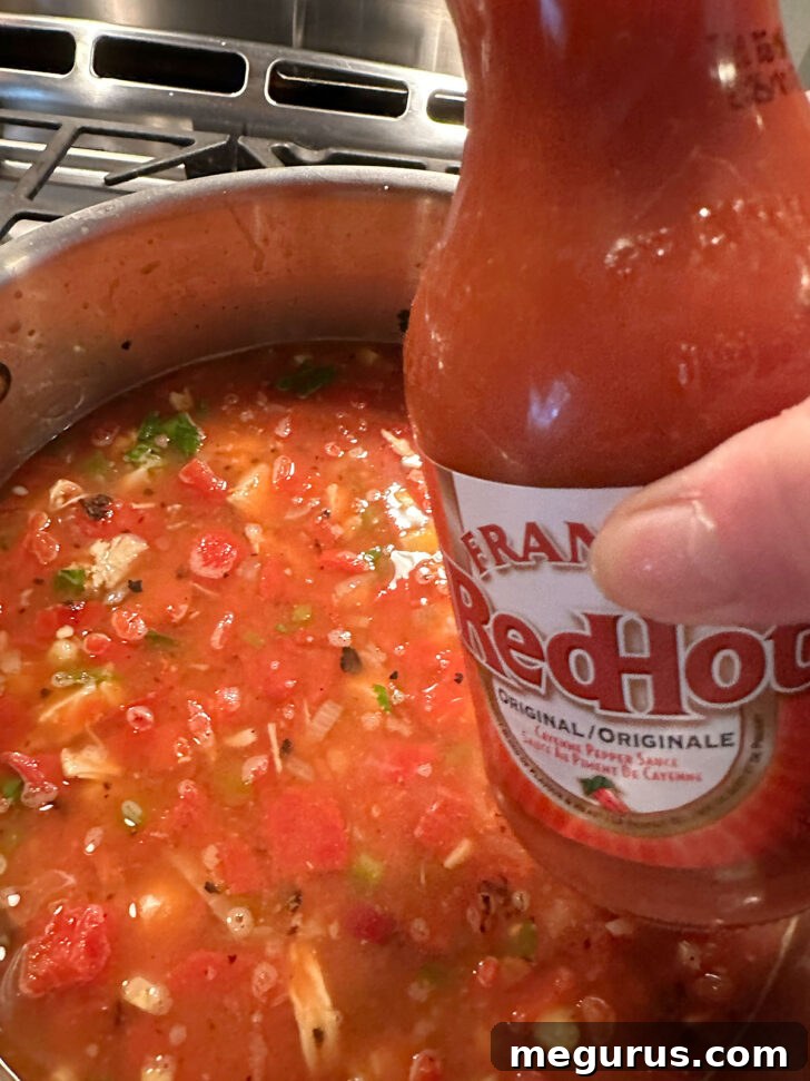 Adding a few drops of hot sauce to the Mexican chicken soup, allowing for customizable heat.