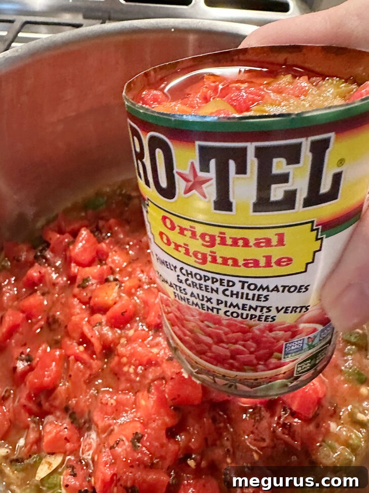 Pouring a can of Ro-Tel diced tomatoes with green chilies into the soup pot, adding extra flavor and a gentle kick.
