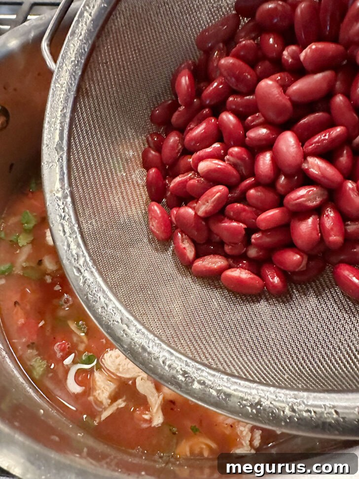 Adding rinsed and drained kidney beans and optional frozen corn to the Mexican chicken soup.