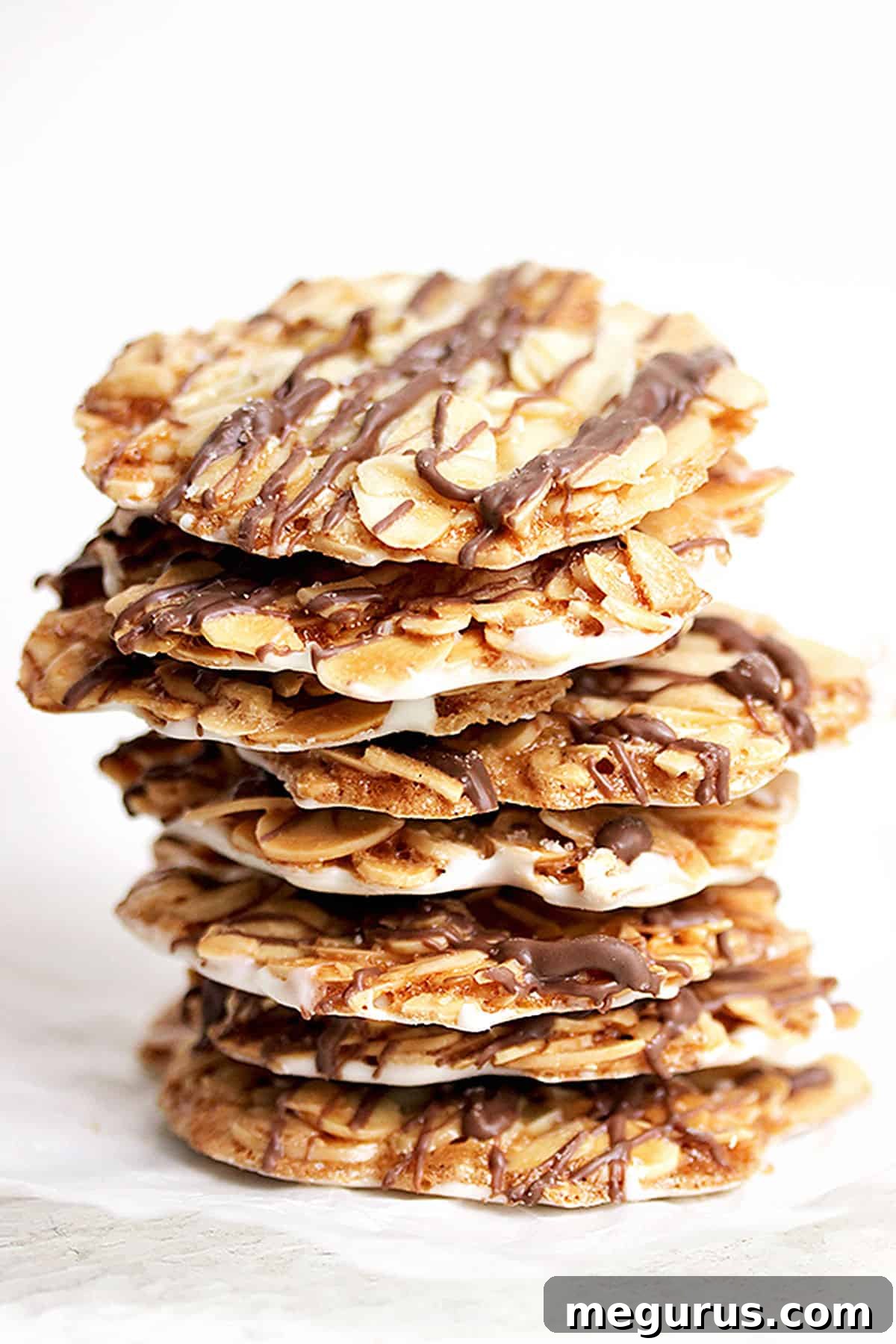 A plate of freshly baked almond Florentine cookies, some with dark chocolate drizzle, ready to be enjoyed.