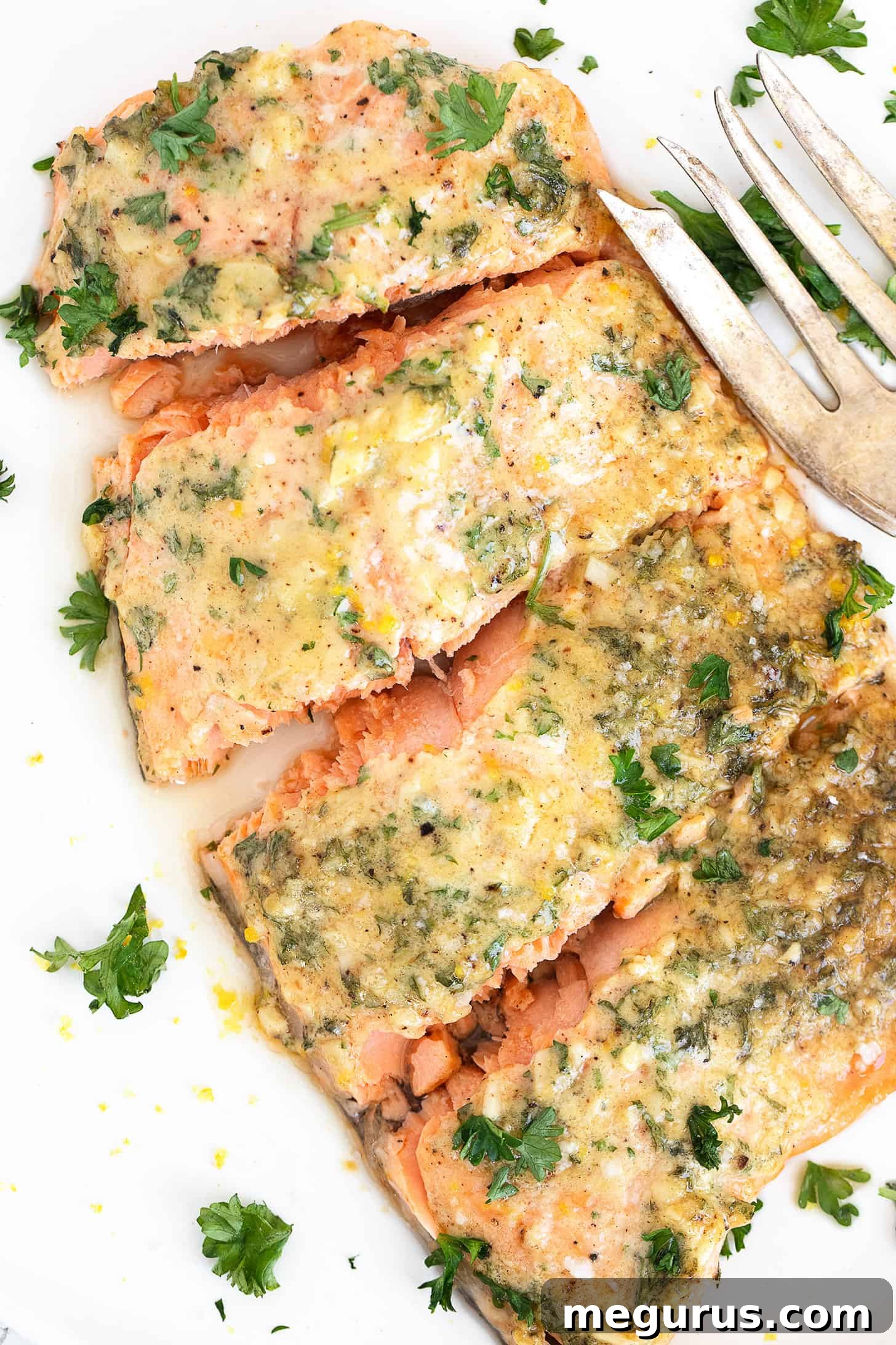 A stunning close-up of the finished Dijon Mustard Garlic Salmon on a white plate, showcasing its golden topping and flaky texture, garnished with fresh herbs.