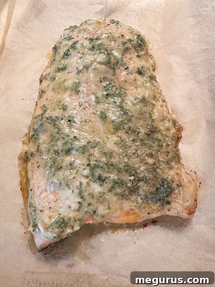 The cooked Dijon garlic salmon, golden and flaky, is shown on the baking sheet after being removed from the oven.
