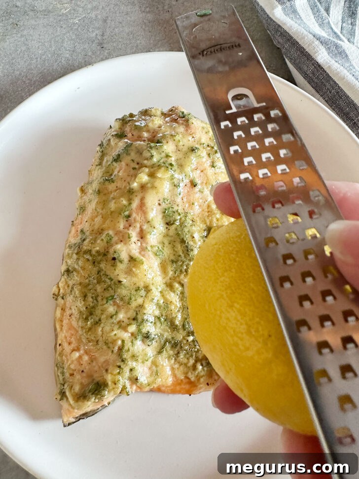A fresh lemon and a grater are positioned, ready to zest the cooked salmon.