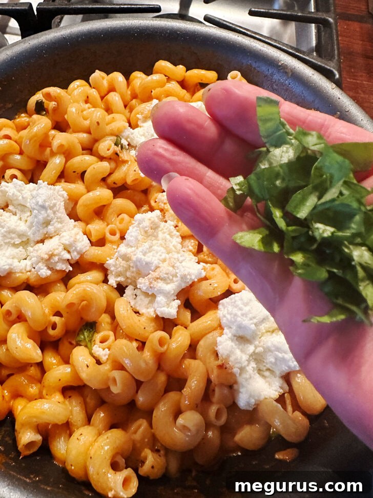 Sprinkling additional fresh basil over the finished pasta dish.