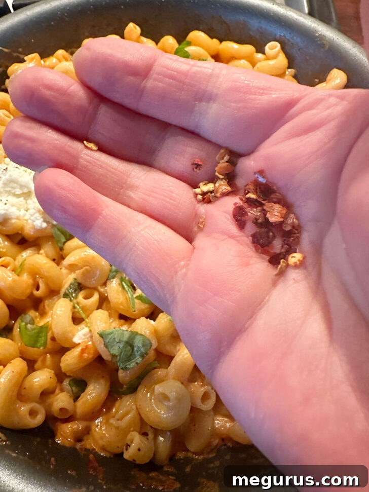 Finishing the creamy vodka tomato ricotta pasta with red pepper flakes.