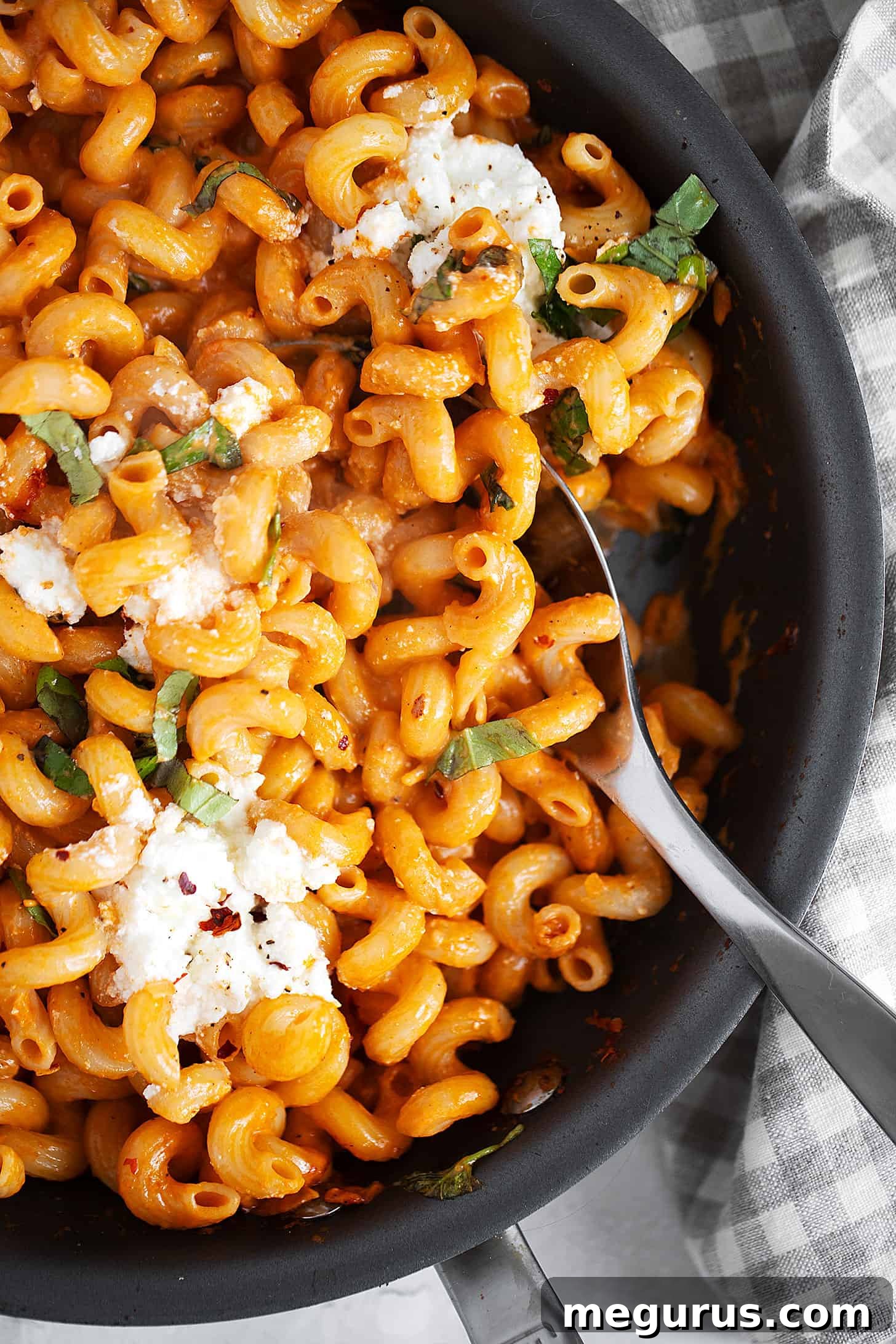 Close-up of vodka tomato ricotta pasta in a skillet with a serving spoon.