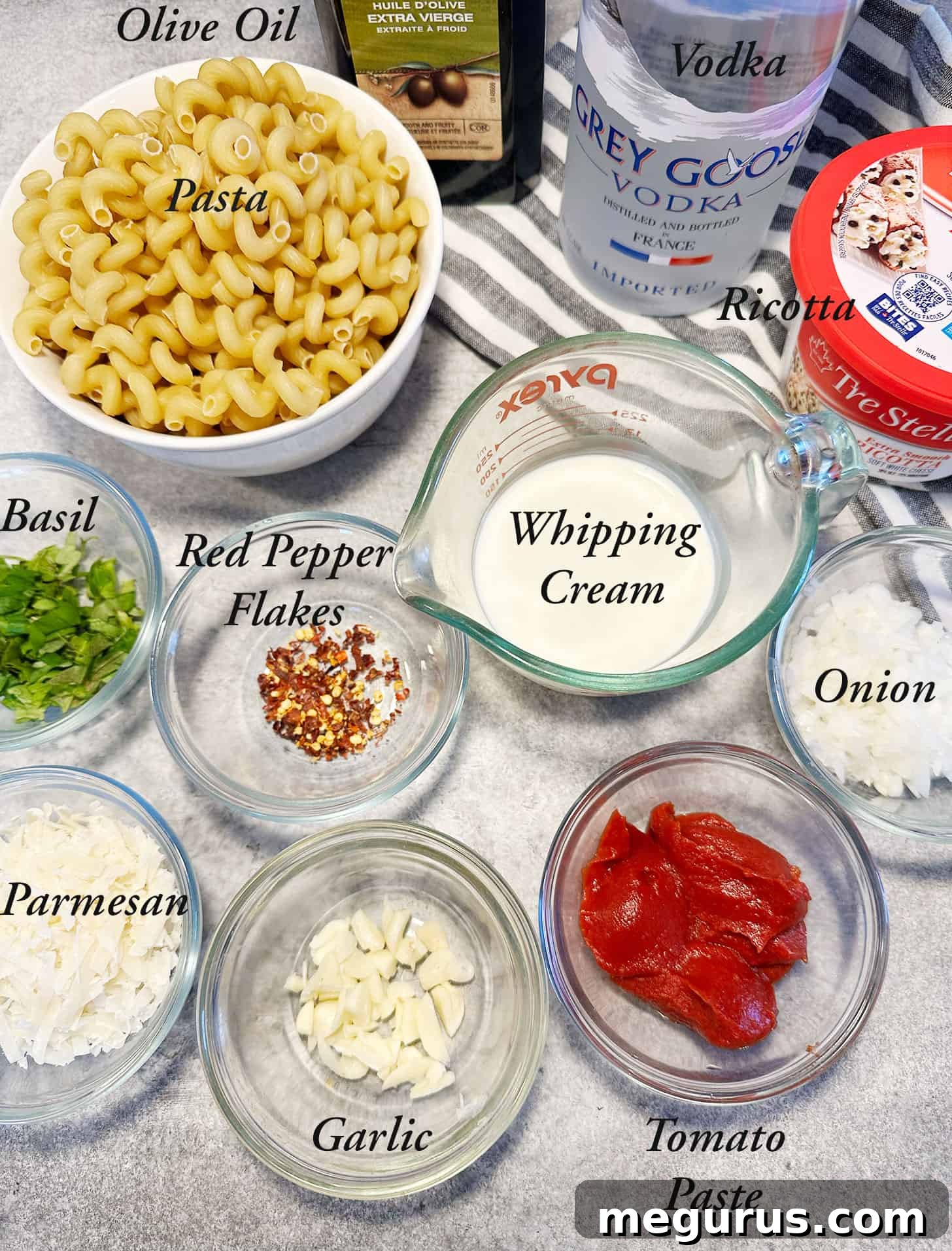 A selection of fresh ingredients including pasta, vodka, tomato paste, cream, ricotta, and basil.