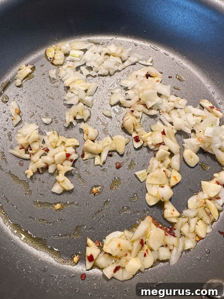 Sautéing onion and garlic with red pepper flakes in a skillet.
