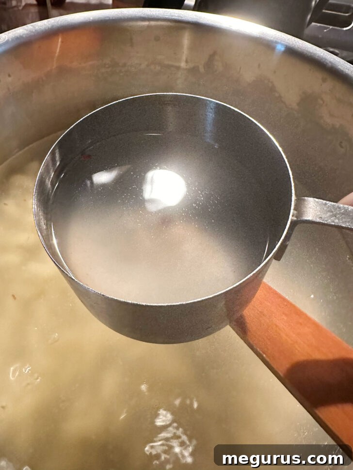 Reserving starchy pasta cooking water in a measuring cup.