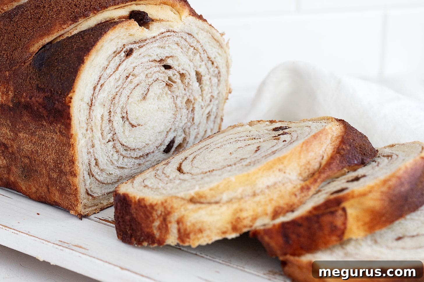 Perfectly sliced Cinnamon Swirl Bread with Raisins on a wooden cutting board, showcasing the beautiful swirl and plump raisins.