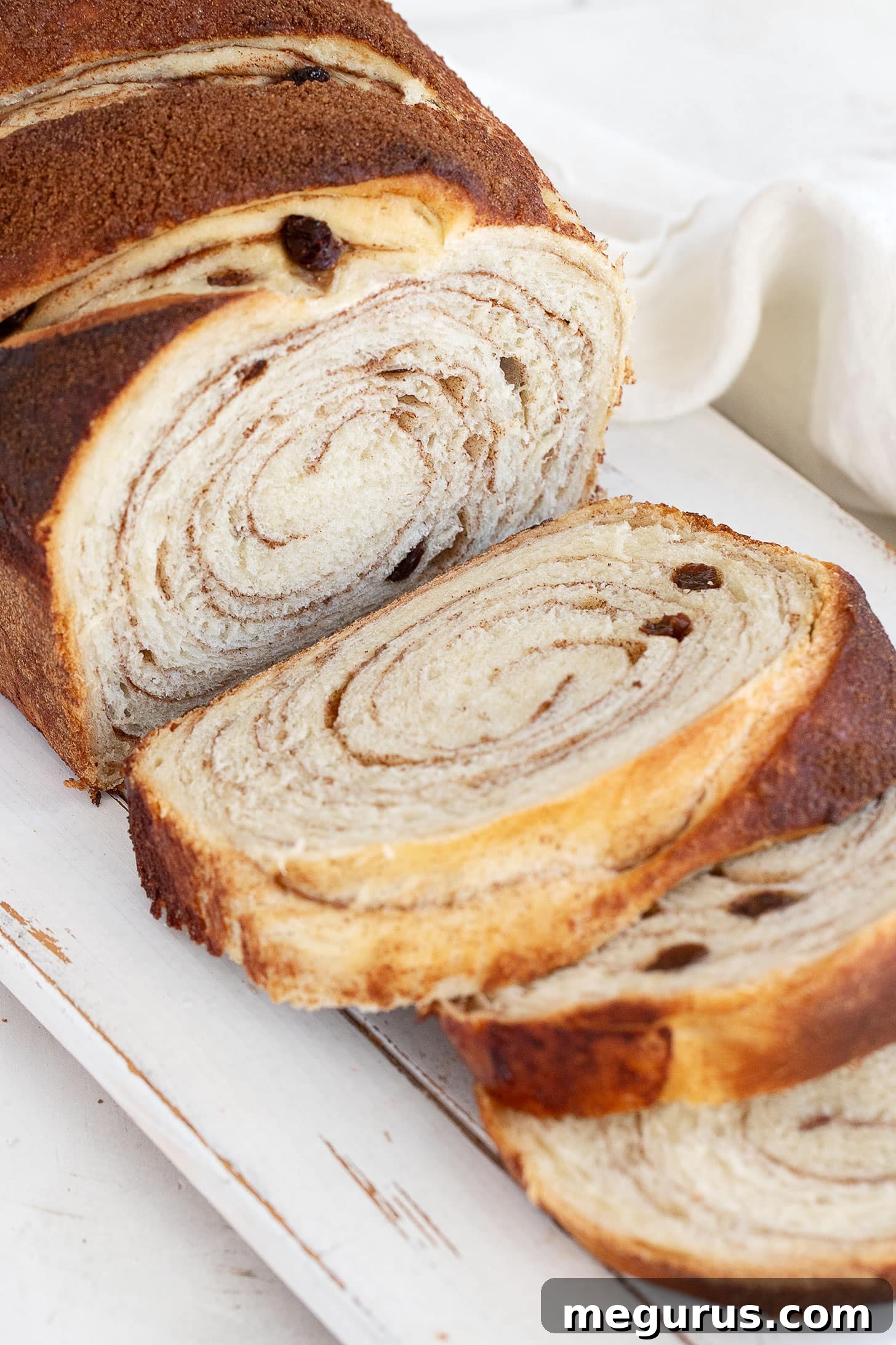 Slices of warm cinnamon swirl raisin bread stacked on a cutting board, ready to be enjoyed.