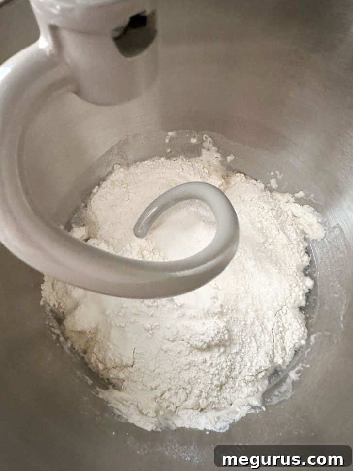 Dough ingredients being combined in a stand mixer bowl.