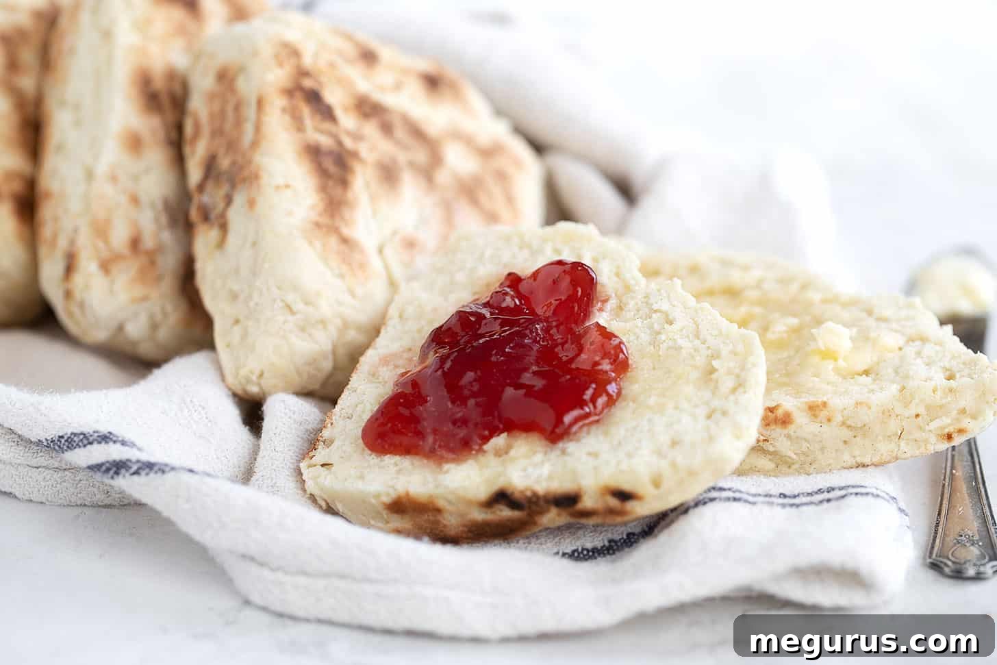 Irish soda farls on a tea towel, split with jam and butter.