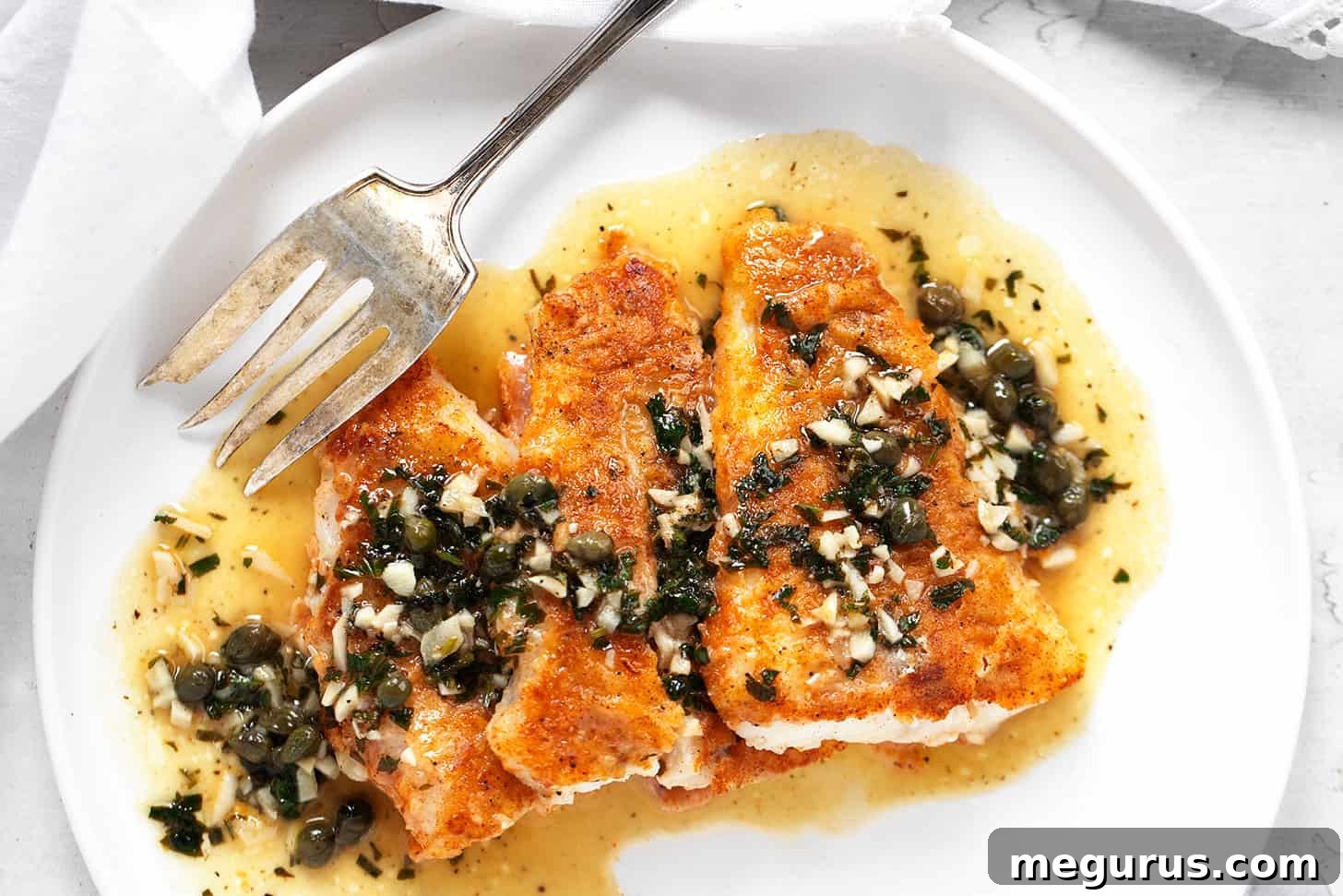 Cod piccata on plate with fork.