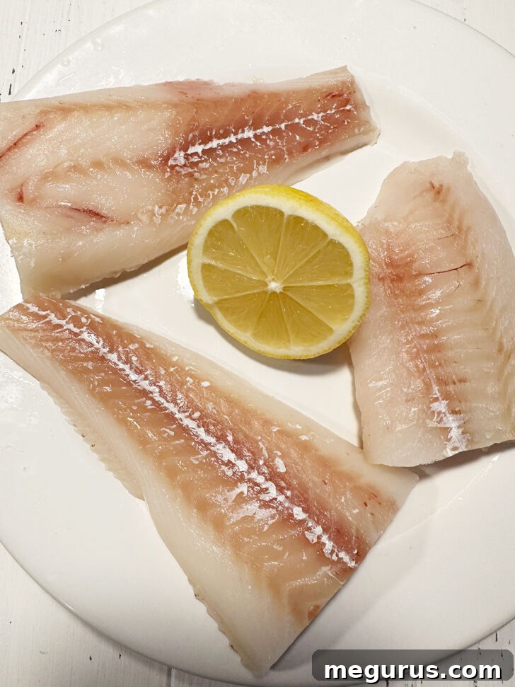 Cod fillets on plate with half a lemon.